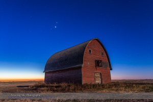 Mars, Venus and Jupiter (in that order from top to bottom) in a triangle, in conjunction, over an old red barn near Vulcan, Alberta, in the morning twilight, October 28, 2015. Illumination is from the nearly Full Hunter’s Moon in the west. The trio of planets were in Leo in a fine conjunction not to be repeated until November 21, 2111.  This is a stack of 6 exposures for the ground, mean combined to smooth noise, and one exposure for the sky, all  10 seconds at f/4 and ISO 800 with the Canon 6D and Canon 24mm lens.