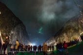A wisp of aurora appears in a break in the clouds as the m/s Nordlys enters Trollfjorden fjord in the Lofoten Islands in Norway, on November 8, 2017. It was actually raining when I took this shot but a major auroral storm was underway and we got a brief glimpse of a curtain as we entered this spectacular and narrow fjord. Then the rain clouds closed in. The bright lights are the ship’s searchlights lighting the walls of the narrow fjord. The white at top is the ship’s smoke. This was from the aft deck looking astern. This was with the 12mm Rokinon fish-eye lens at f/2.8 for 1.6 seconds with the Nikon D750 at ISO 6400.