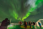 Aurora tourists watch and photograph the Northern Lights from the deck of the m/s Nordlys in October 2017 on the coast of Norway.