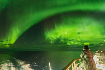 A participant in the Road Scholar aurora tour in October 2017 watches the Northern Lights from the aft deck of the m/s Nordlys on the Norway coast. The Big Dipper is at centre