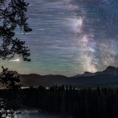 The stars trailing as they move east to west (left to right), ending with the Milky Way and Galactic Centre (right) over Storm Mountain and the Vermilion Pass area of the Continental Divide in Banff National Park, Alberta. Mars is the bright trail at left. Saturn is amid the Milky Way at right. This was July 15, 2018. The lights at left are from the Castle Mountain interchange at Highways 1 and 93. This is a stack of 8 exposures, mean combined to smooth noise, for the ground, plus 200 exposures for the star trails, and one exposure, untracked, for the fixed sky taken about a minute after the last star trail image. All 30 seconds at f/2.8 with the 24mm Sigma lens, and Nikon D750 at ISO 6400. The frames were taken as part of a time-lapse sequence. Dynamic Contrast filter from ON1 applied to the ground, and Soft and Airy filter from Luminar applied to the sky for a soft Orton effect.