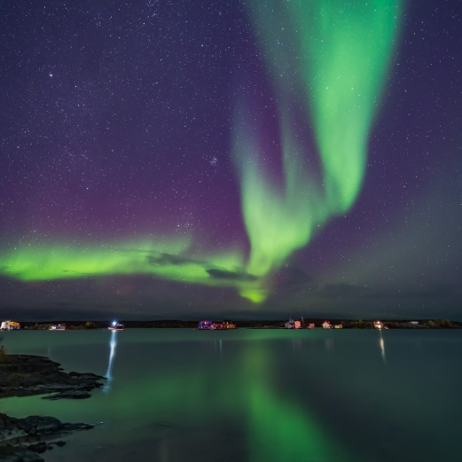 A curtain of aurora sweeps over the houseboats moored on Yellowknife Bay in Yellowknife, NWT, on September 11, 2018. The Pleiades and Hyades star clusters in Taurus are rising at left. This is a mean-combined stack of 8 images to smooth noise for the ground and water, and a single exposure for the sky and houseboats themselves (as they were moving slightly from exposure to exposure). Each was 13 seconds at f/2 with the Venus Optics 15mm lens and Sony a7III at ISO 3200.