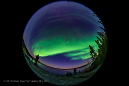 A 360° fish-eye view of the Northern Lights over Prelude Lake near Yellowknife, NWT, Canada, on September 9, 2019, with photographers in the foreground shooting the Lights from the viewpoint above the lake. Polaris is near the centre; the Big Dipper and Ursa Major are at lower left; Cassiopeia is at upper right. Andromeda and Pegasus are rising at far right. Arcturus is setting at far left. This is a single shot with the 8mm Sigma lens at f/3.5 on the Sony a7III for 10 seconds at ISO 3200. Moonlight also provides some of the illumination. Accent AI filter applied to the ground with Topaz Studio 2.0